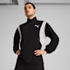 Un mannequin pose sur fond gris, veste Puma noire et blanche, mains sur les hanches.