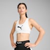 Una modella posa su uno sfondo grigio, indossando un top bianco e leggings neri.