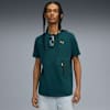 Un modello posa su sfondo grigio, con t-shirt verde e pantaloncini chiari.