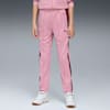 Un modèle se tient sur fond gris, portant un pantalon de survêtement rose et des baskets blanches.