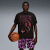 Een model houdt een basketbal vast tegen een grijze achtergrond, draagt een grafisch T-shirt en doodskopshorts.