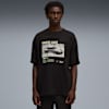 Un modello posa su sfondo grigio, con una t-shirt nera con grafica di un'auto.