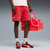 Op grijs houdt een model een rode tas vast, draagt een rode korte broek en zwart-rood-witte sneakers.