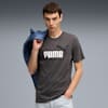 Un mannequin pose sur fond gris, portant un t-shirt Puma et tenant une veste bleue.