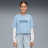 Un mannequin pose sur fond gris, portant un T-shirt PUMA bleu, un jean et un haut blanc à manches longues.