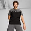 Su sfondo grigio, un modello posa con una t-shirt con logo nera, grigia e bianca.