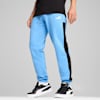 Su sfondo grigio, un modello indossa pantaloni azzurri e scarpe da ginnastica nere.
