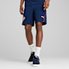 Vor grauem Hintergrund steht ein Model mit marineblauen Shorts, weißen Socken und blauen Turnschuhen.