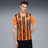 Sur fond gris, un mannequin porte un maillot de football rayé orange et noir.