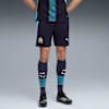 Een model draagt een voetbaltenue tegen een grijze achtergrond, met marineblauwe shorts en sokken.