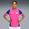 A model poses against a grey backdrop, wearing a pink and blue sports shirt.