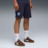 Su sfondo grigio, un modello indossa pantaloncini blu navy, calzini bianchi e scarpe da ginnastica marroni.
