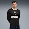 Ein Model posiert vor grauem Hintergrund mit schwarzem St. Pauli-Langarmtrikot und Jeans.