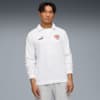 Ein Model posiert vor Grau, trägt ein weißes Langarmshirt und graue Trainingshose.