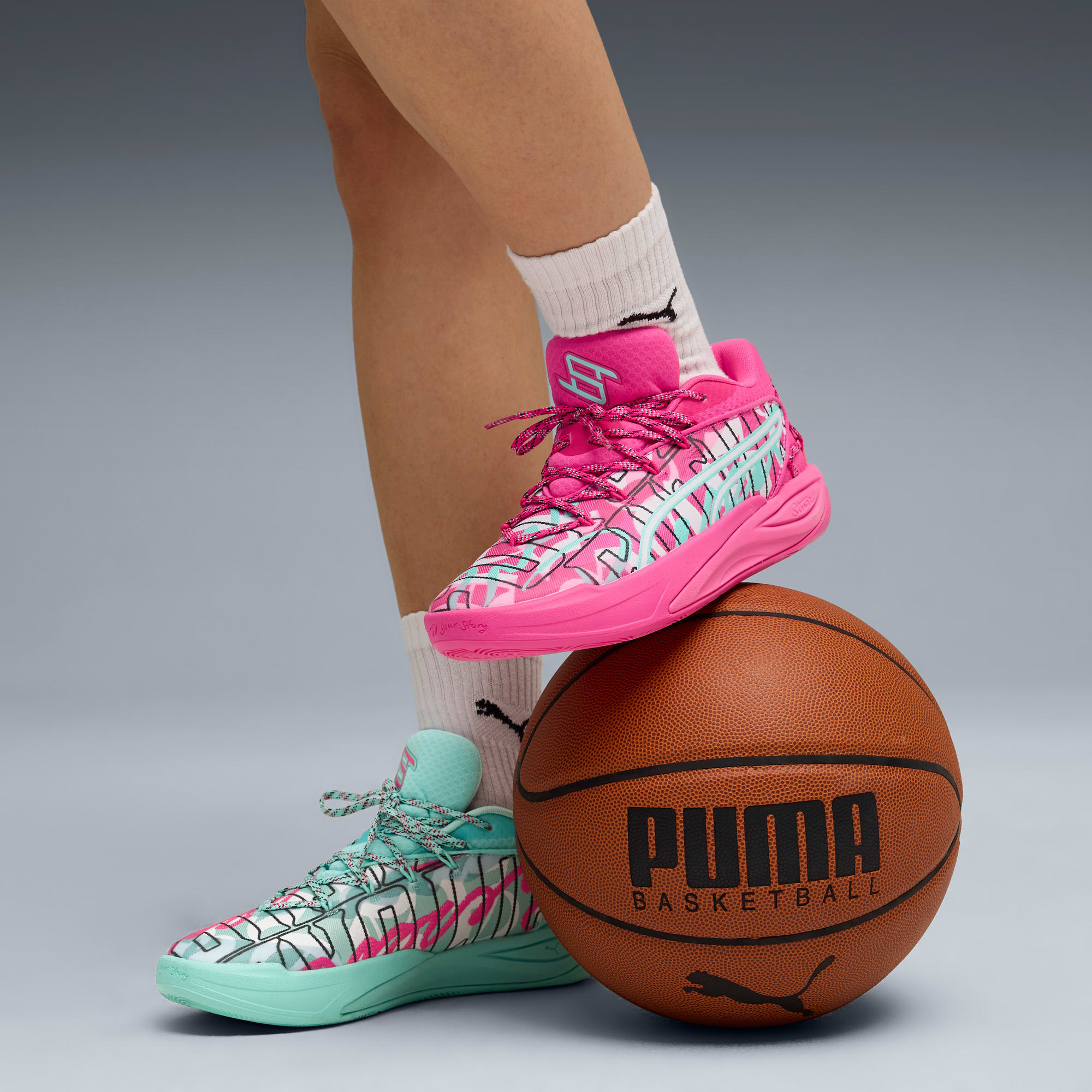 Op grijs balanceert een model in roze sneakers op een basketbal.