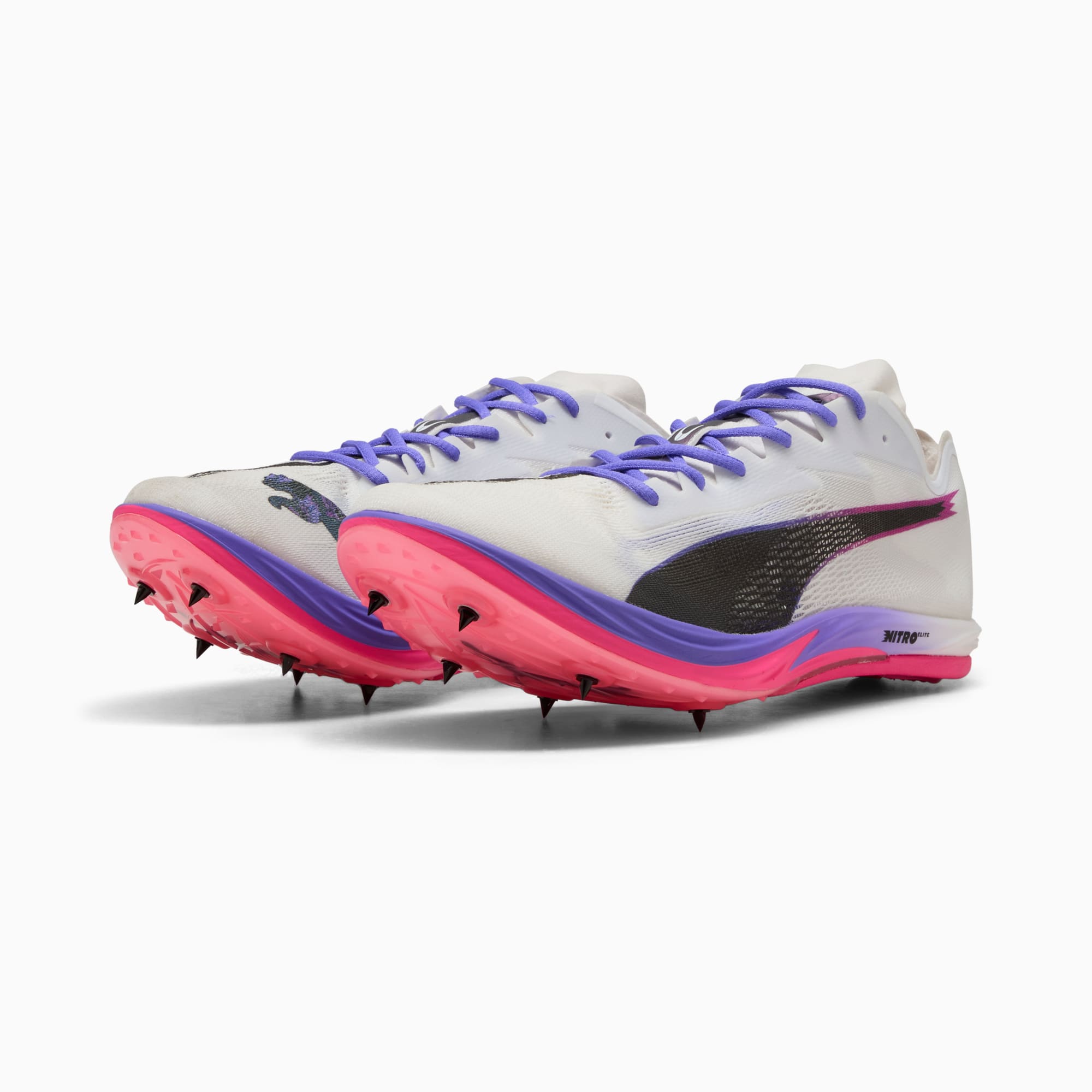 Scarpe chiodate PUMA unisex bianche con suola rosa, viola e logo nero.