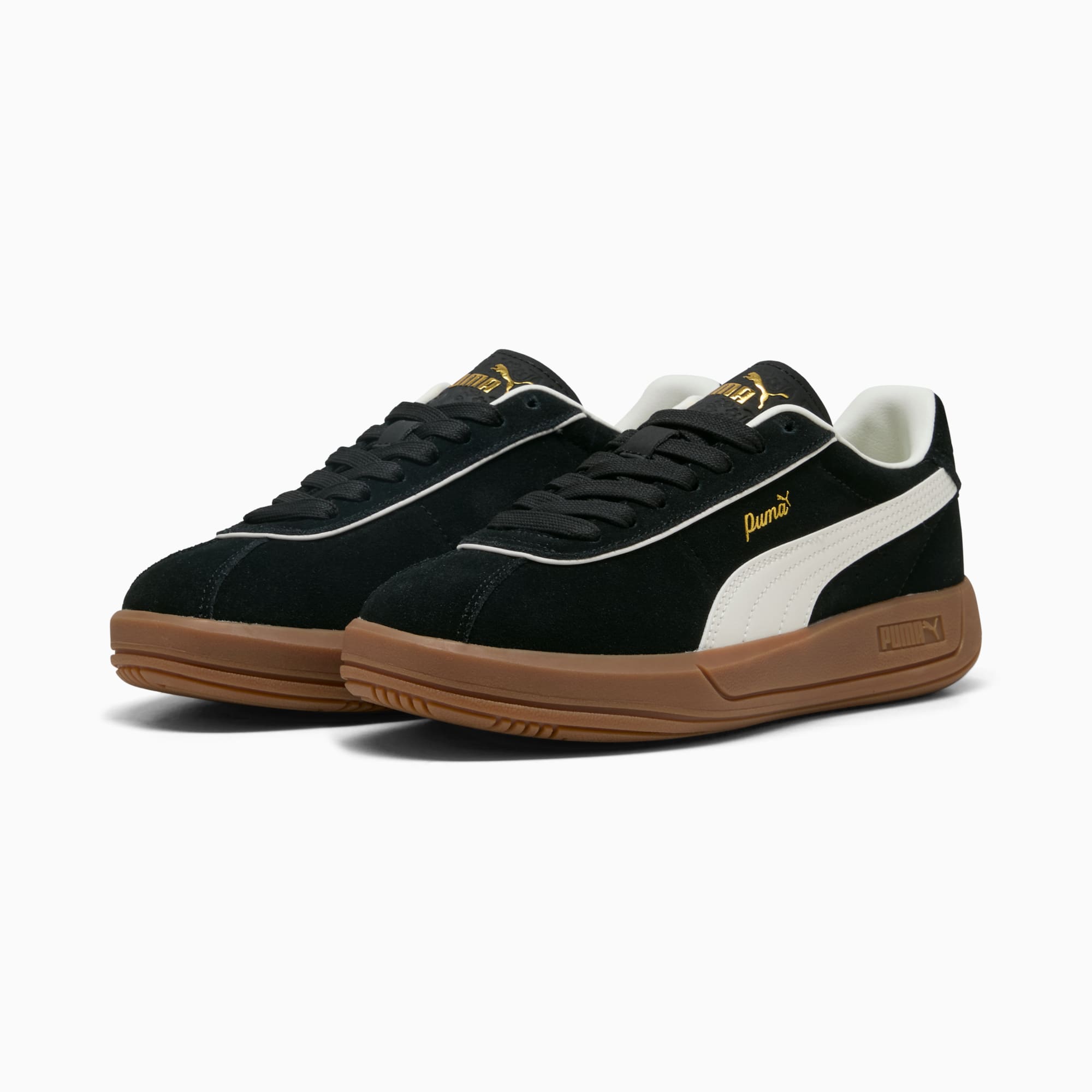 Sneakers PUMA nere con striscia bianca, logo dorato e suola marrone.