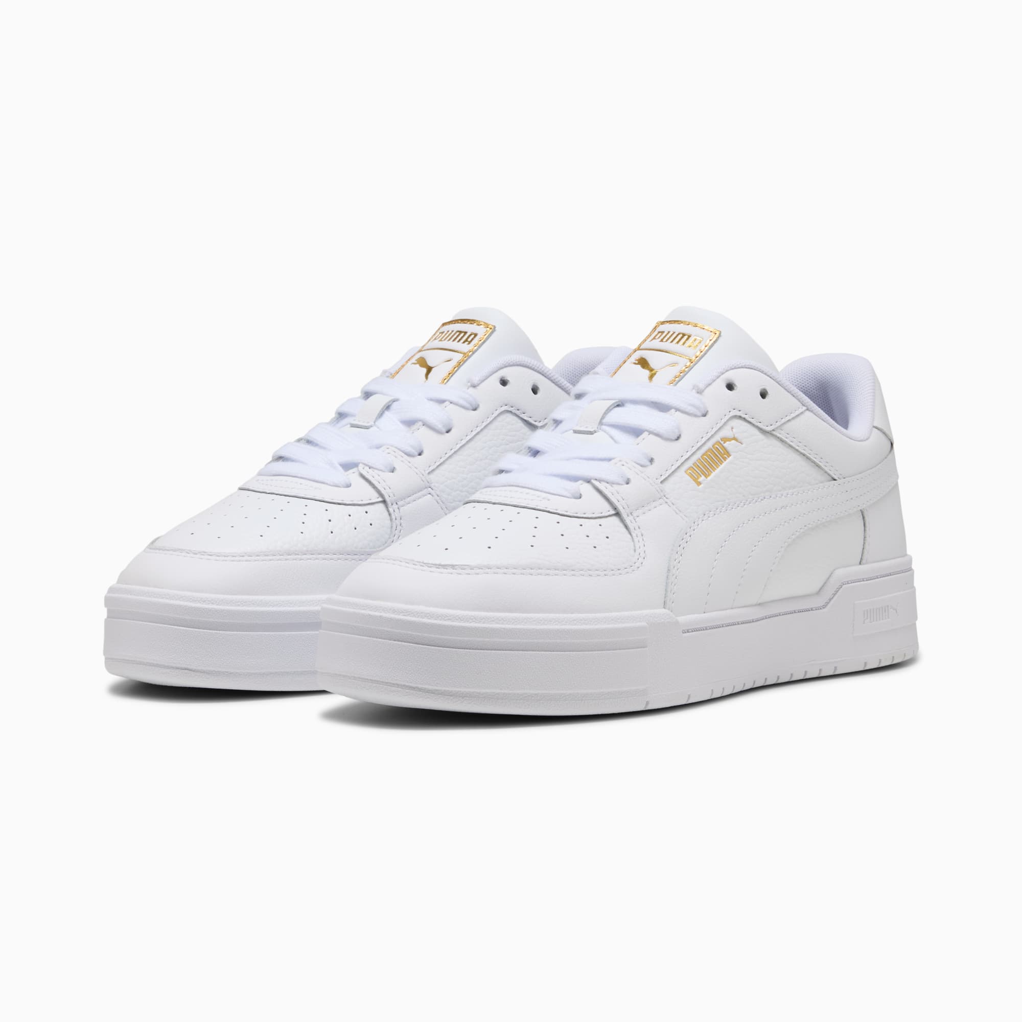 White PUMA trainers for adults, with gold logo and lace-up fastening.