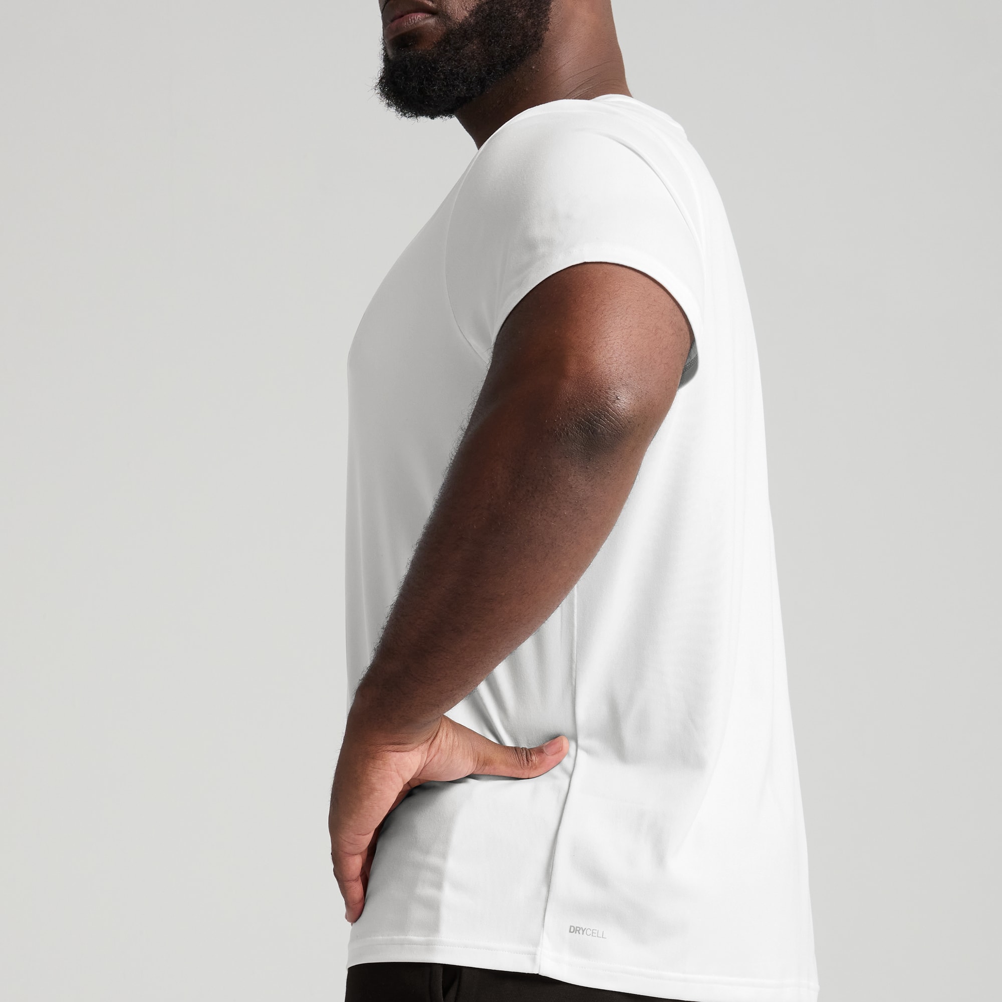 Un modèle pose sur fond gris, portant un t-shirt blanc et un bas noir.