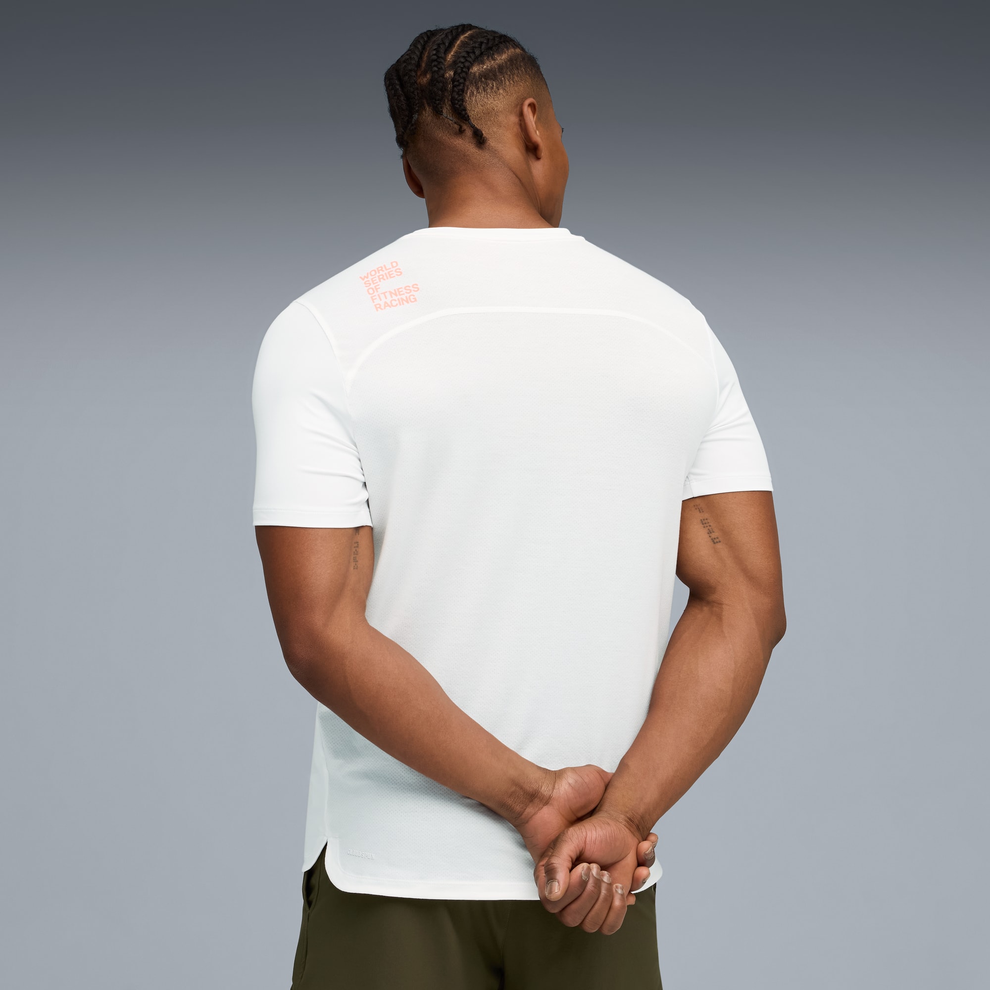 Ein Model mit dem Rücken zum Betrachter vor grauem Hintergrund, trägt ein weißes T-Shirt und Khaki-Shorts.