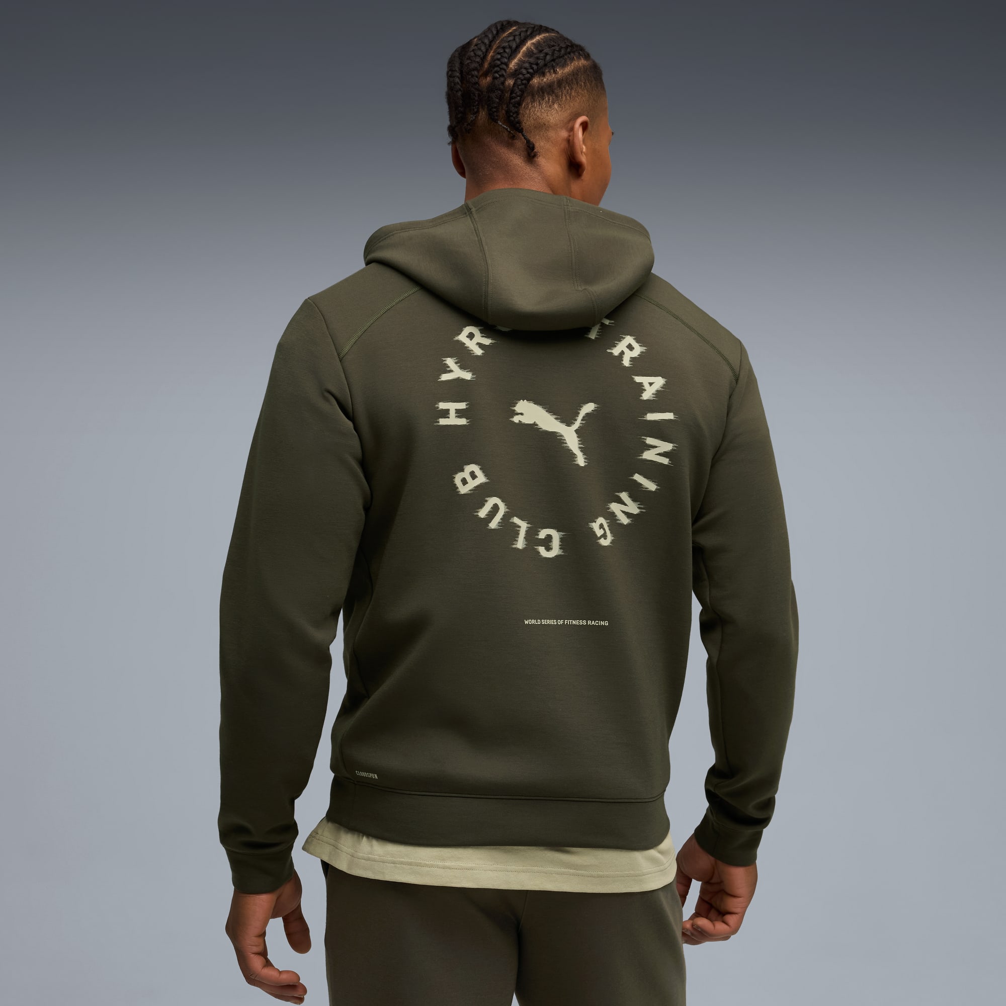 Sur un fond gris, un modèle est vu de dos portant un sweat à capuche olive.