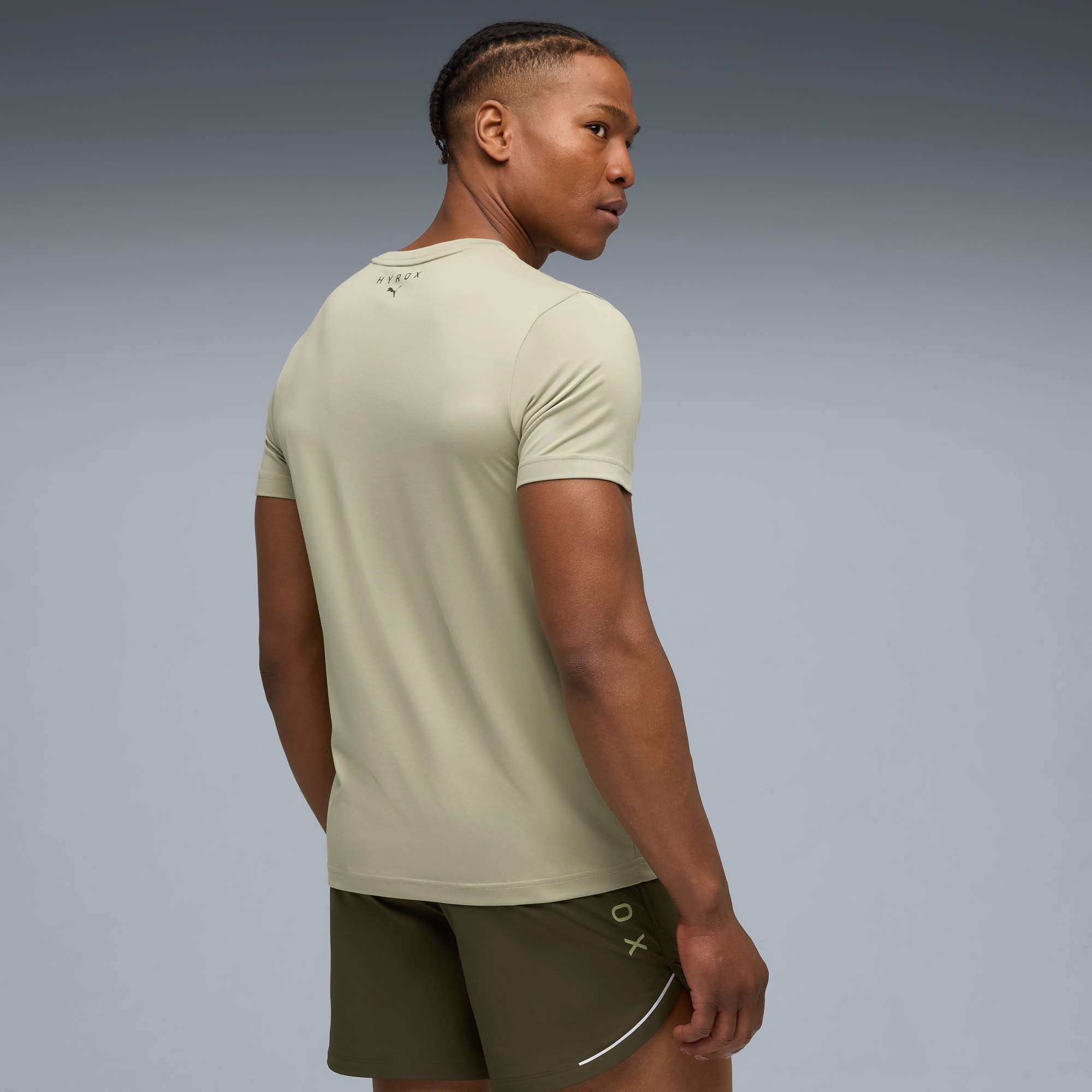 Ein Model vor grauem Hintergrund, das wegschaut und ein T-Shirt und Shorts trägt.