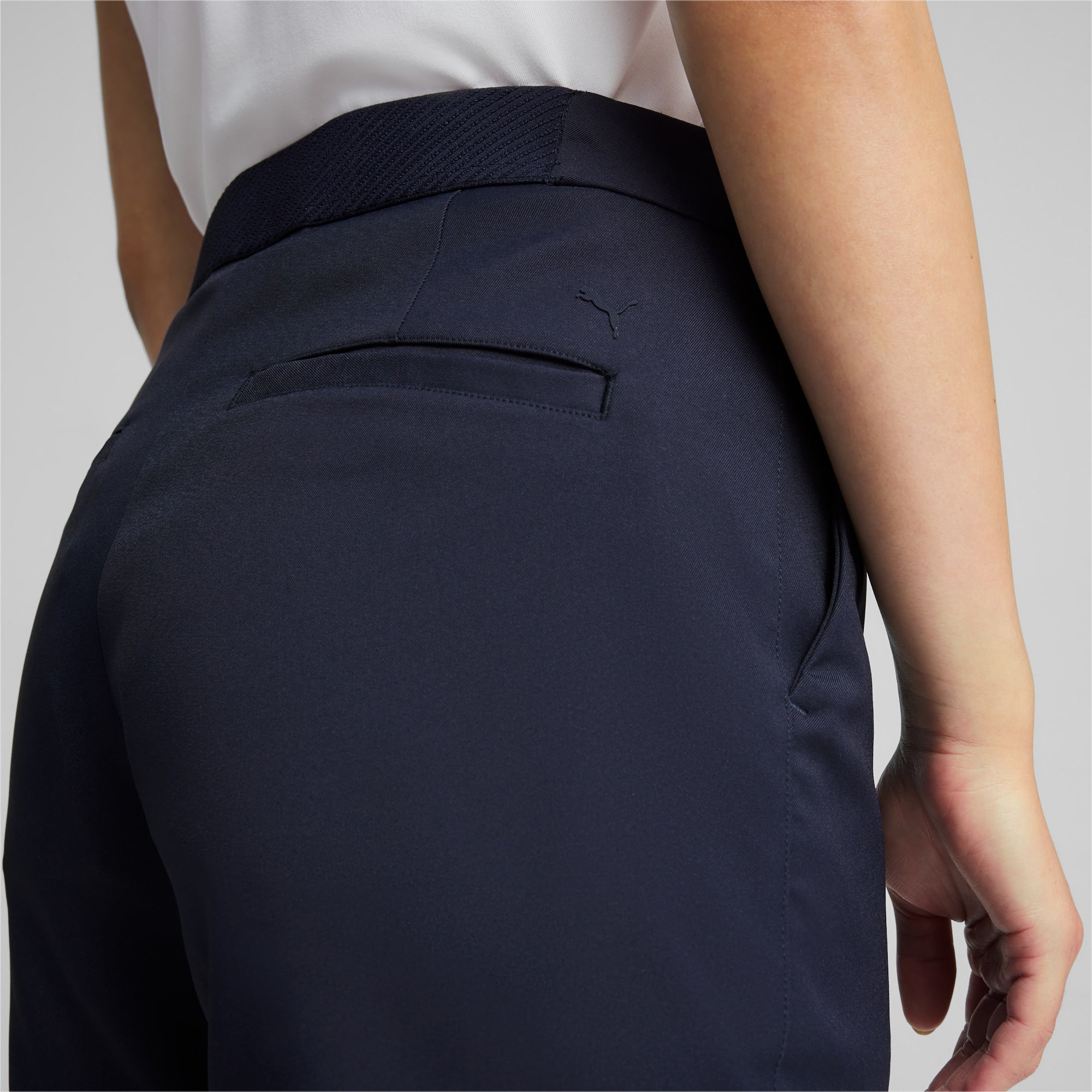 Primo piano di una modella che indossa pantaloni blu navy su sfondo grigio.