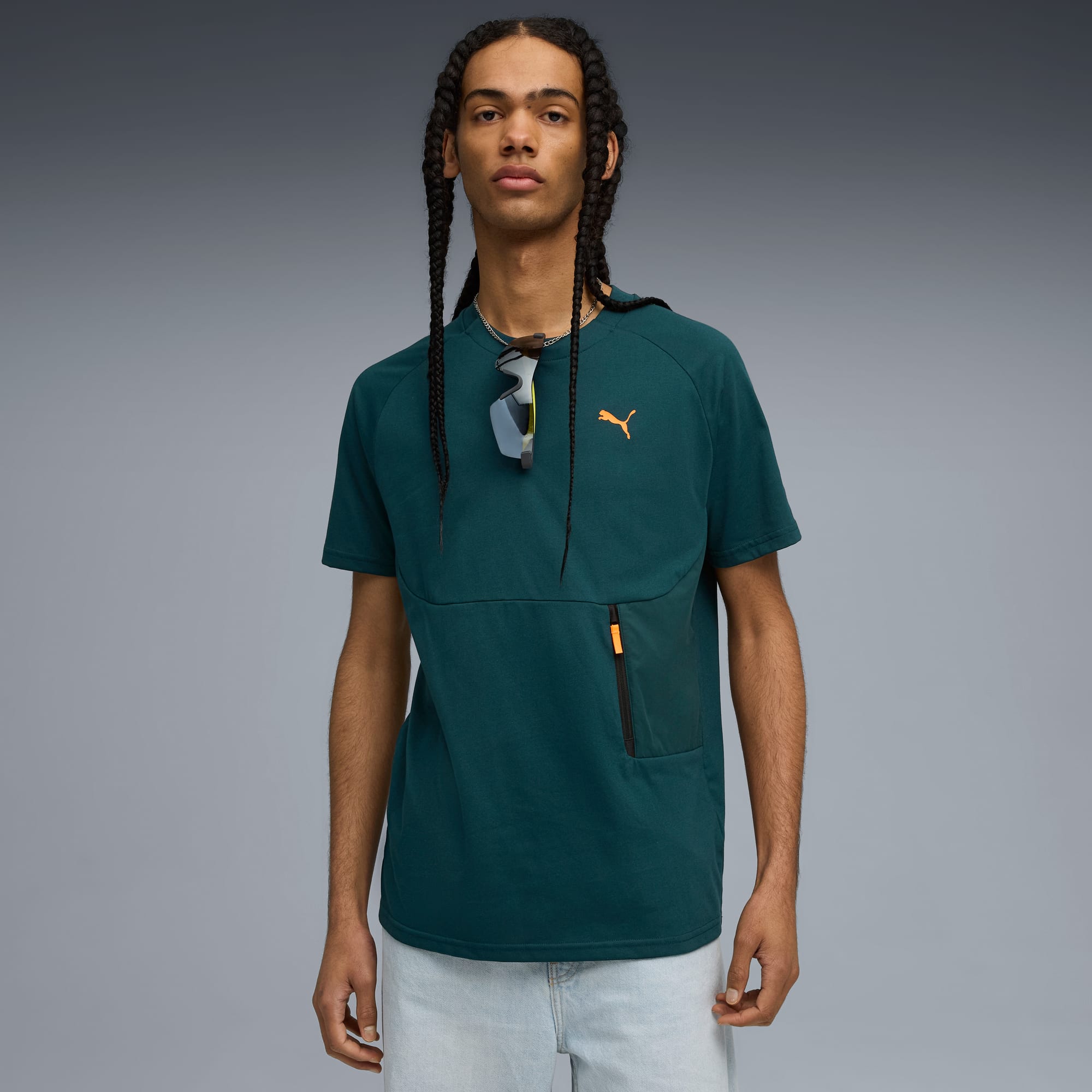 Un modello posa su sfondo grigio, con t-shirt verde e pantaloncini chiari.