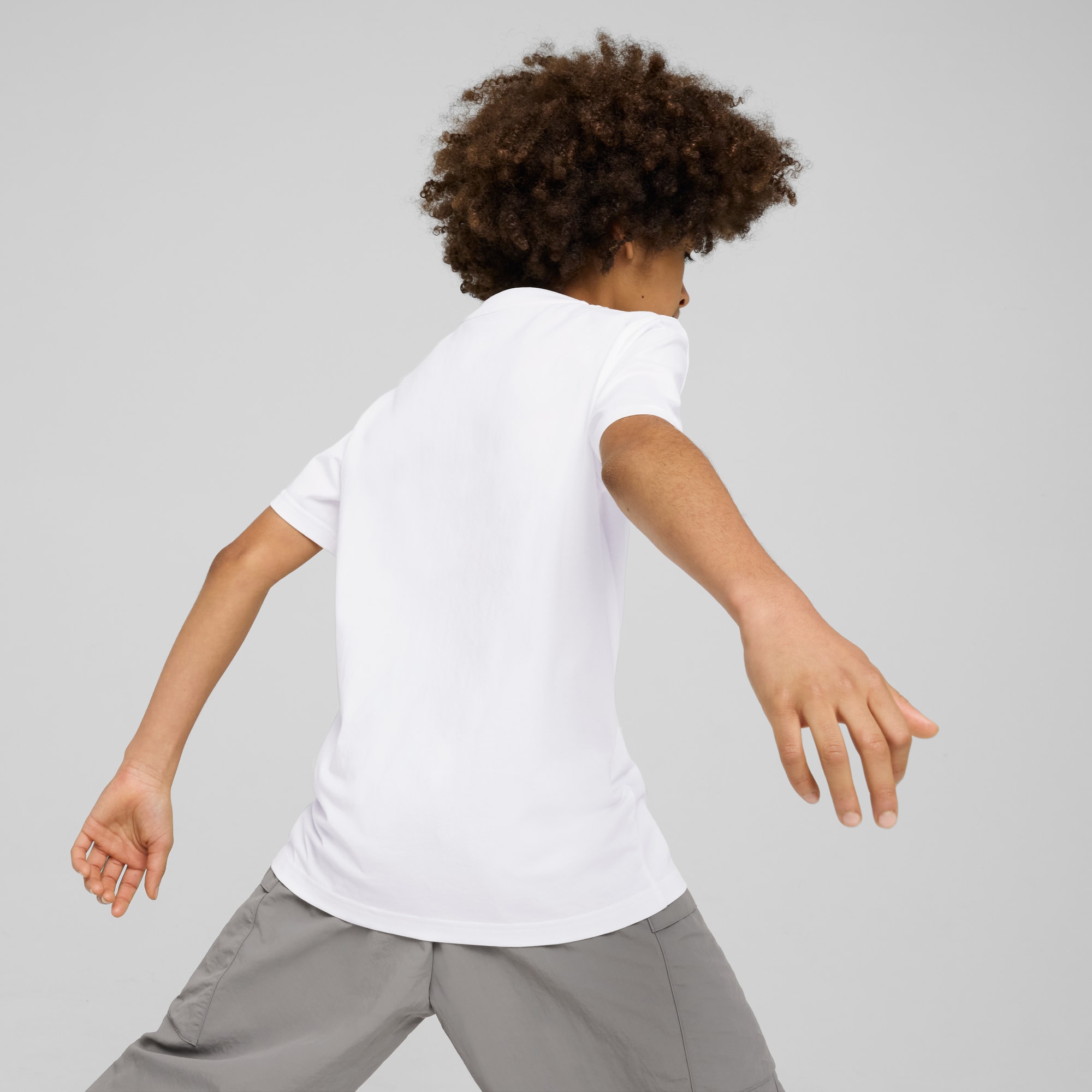 Un modello su sfondo grigio, in movimento, con maglietta bianca e pantaloni grigi.