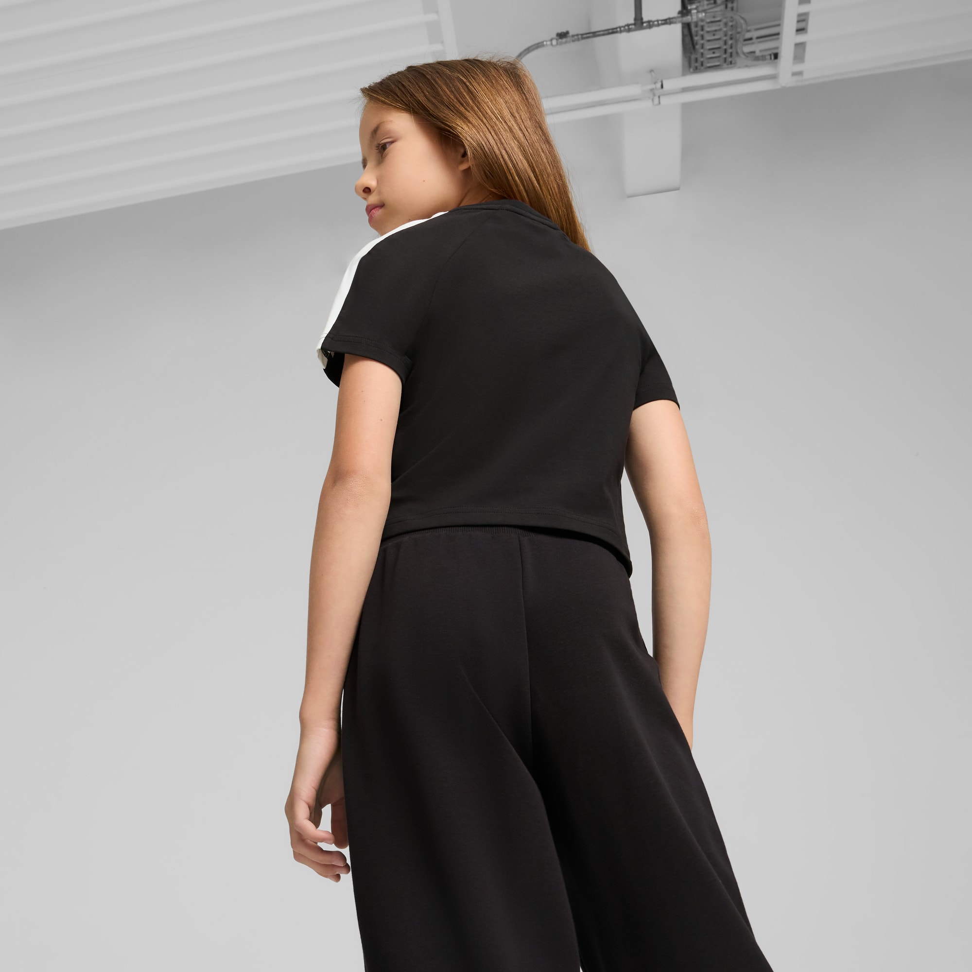 Un modèle sur fond gris portant un haut noir et un pantalon noir.