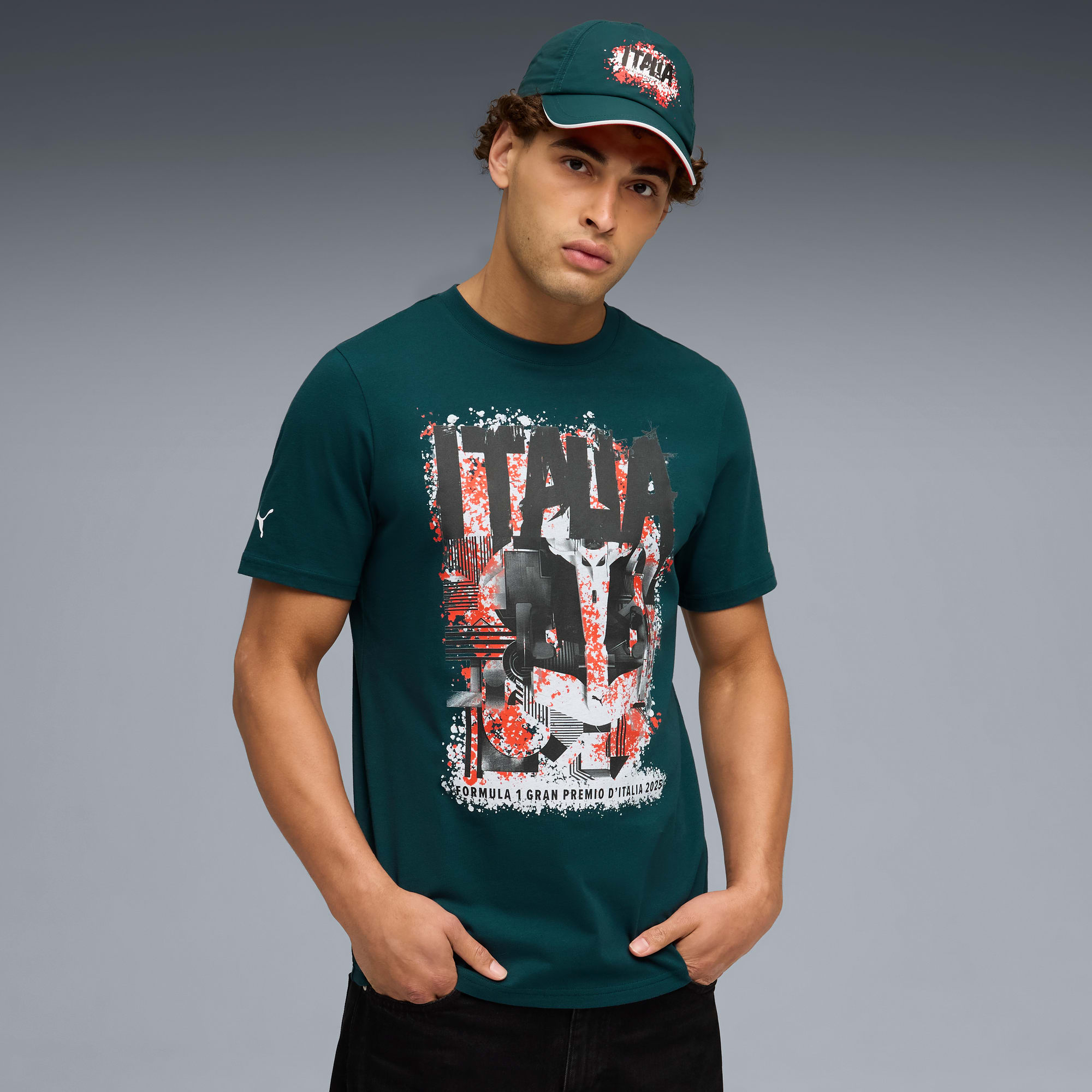 Ein Model posiert vor grauem Hintergrund mit Kappe und dunkelgrünem Grafik-T-Shirt.