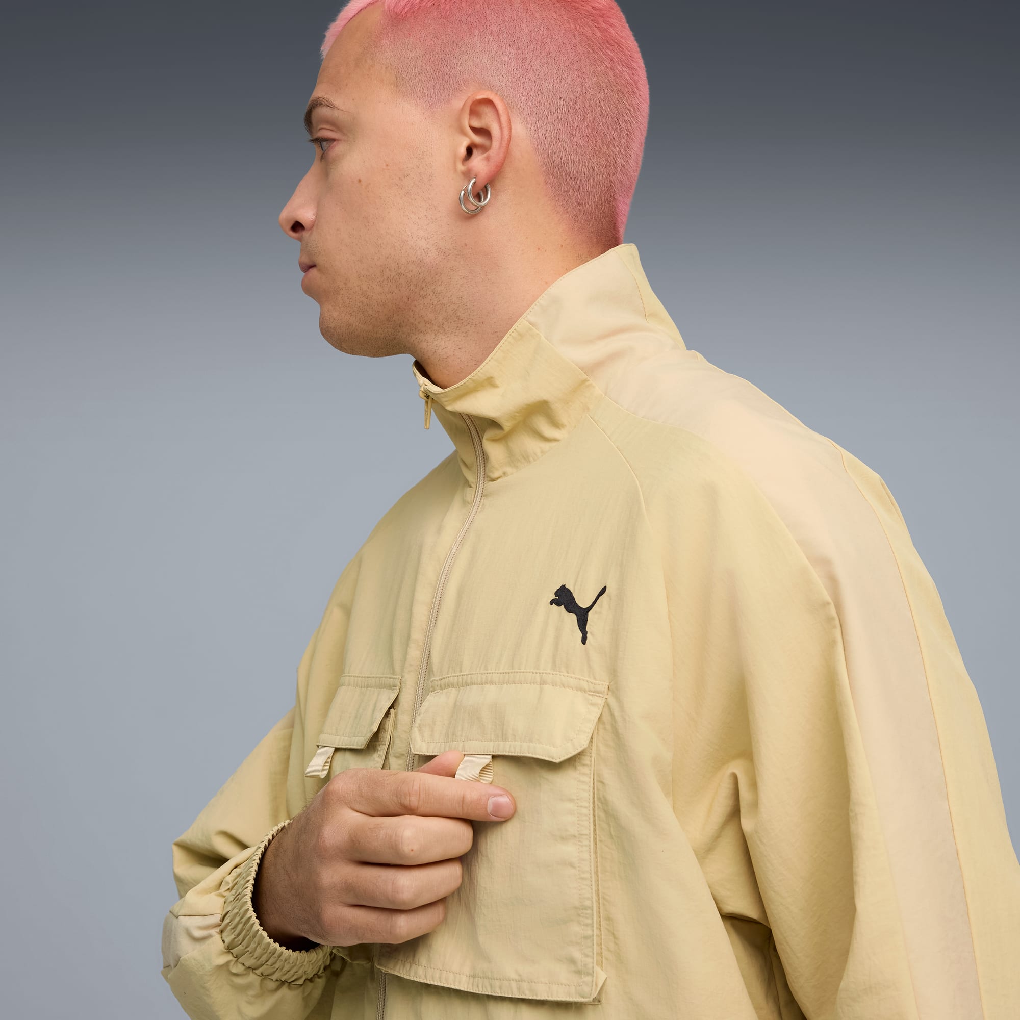 Un modèle sur fond gris portant une veste beige avec un logo noir.