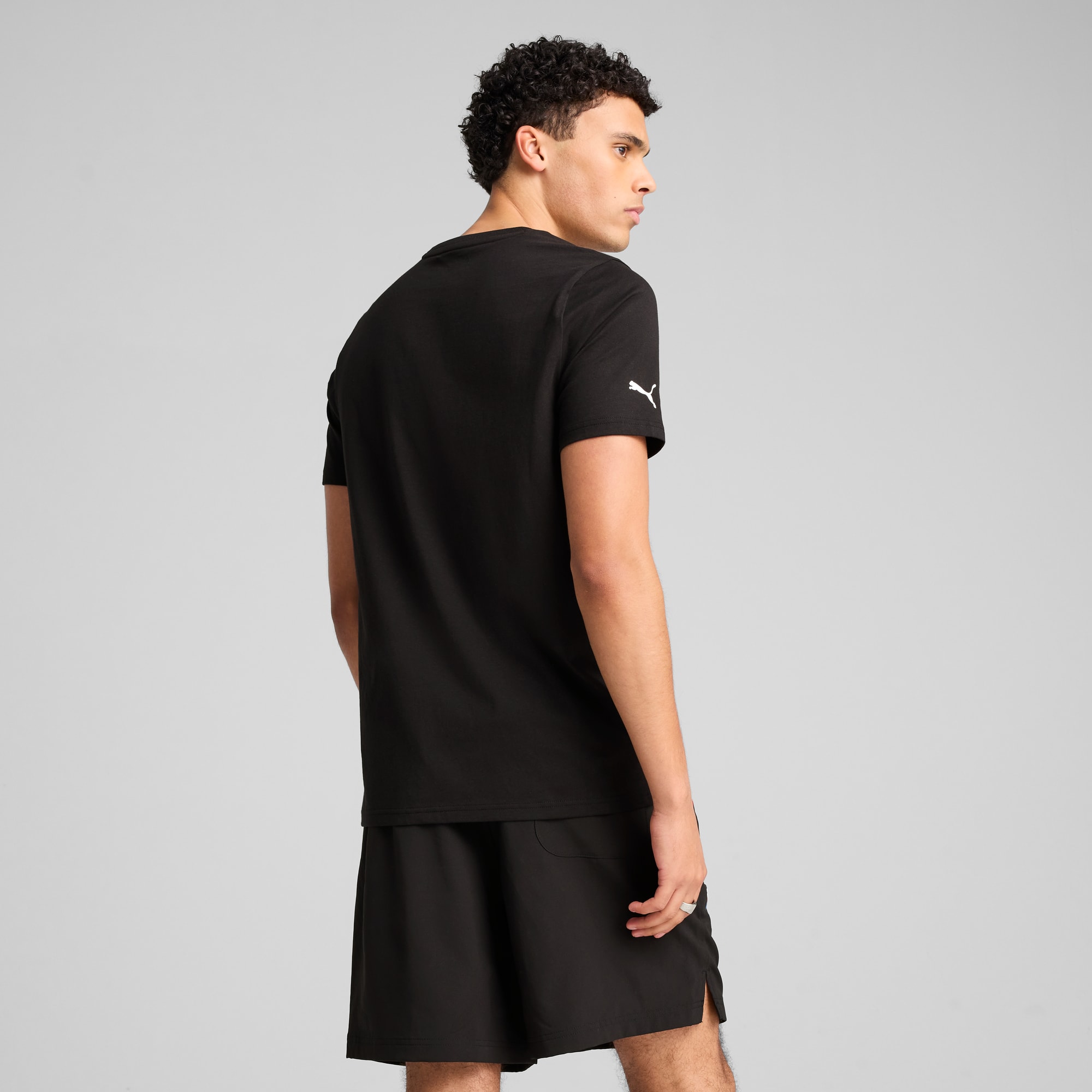 Un modello posa in t-shirt e pantaloncini neri su sfondo grigio.