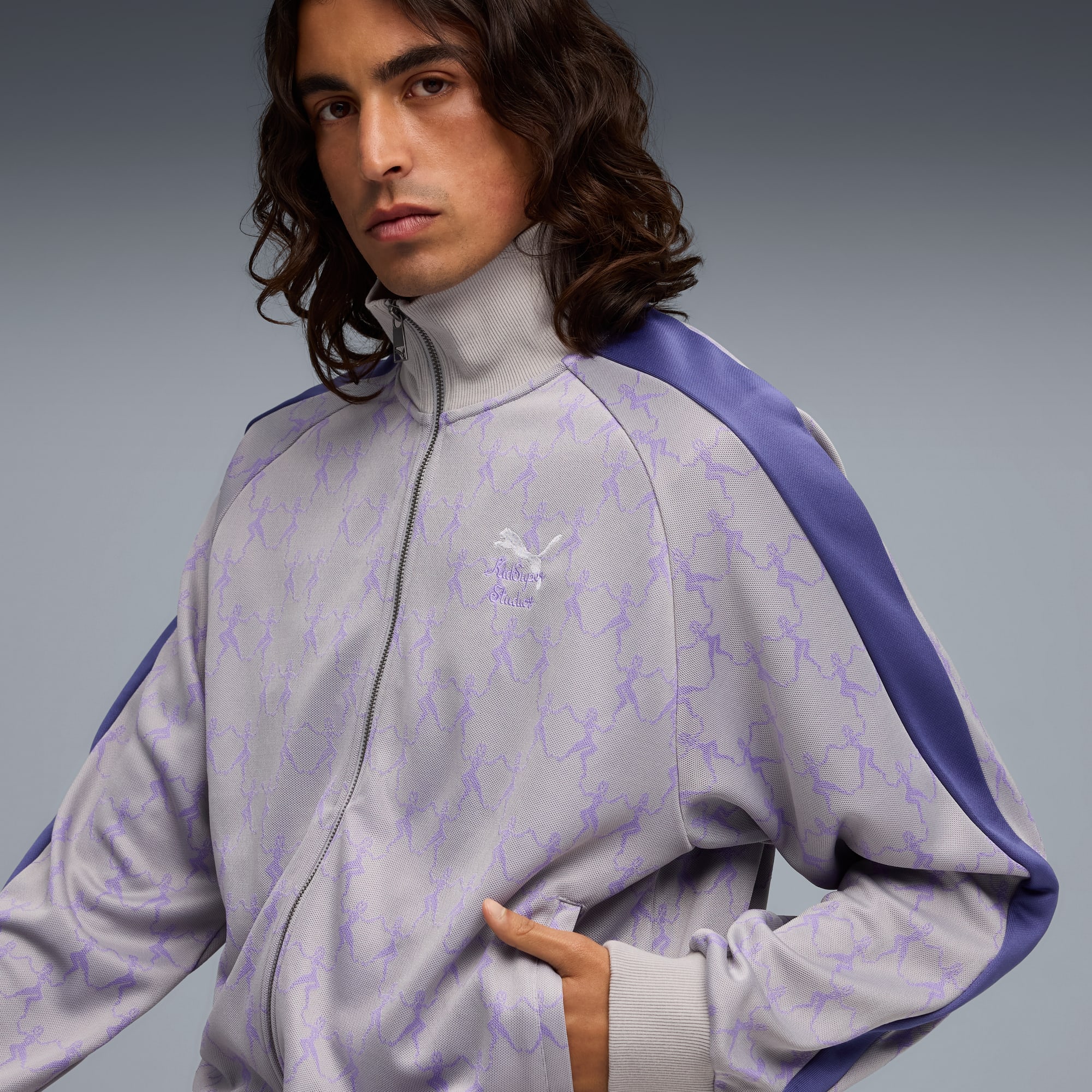 Un modelo posa sobre gris con una chaqueta con cremallera estampada y detalles morados.