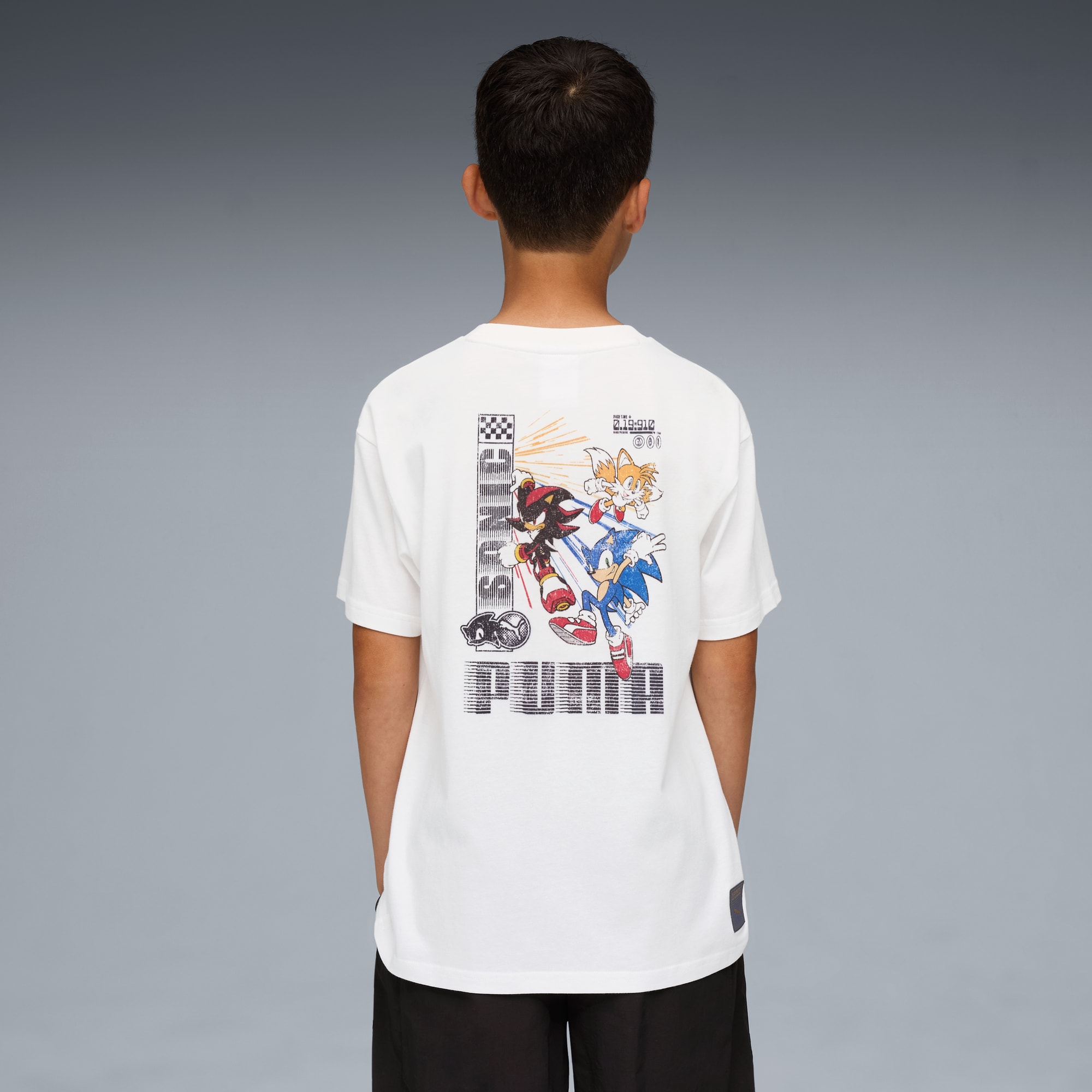 Su sfondo grigio, un bambino indossa una t-shirt bianca con personaggi di Sonic e il logo PUMA.