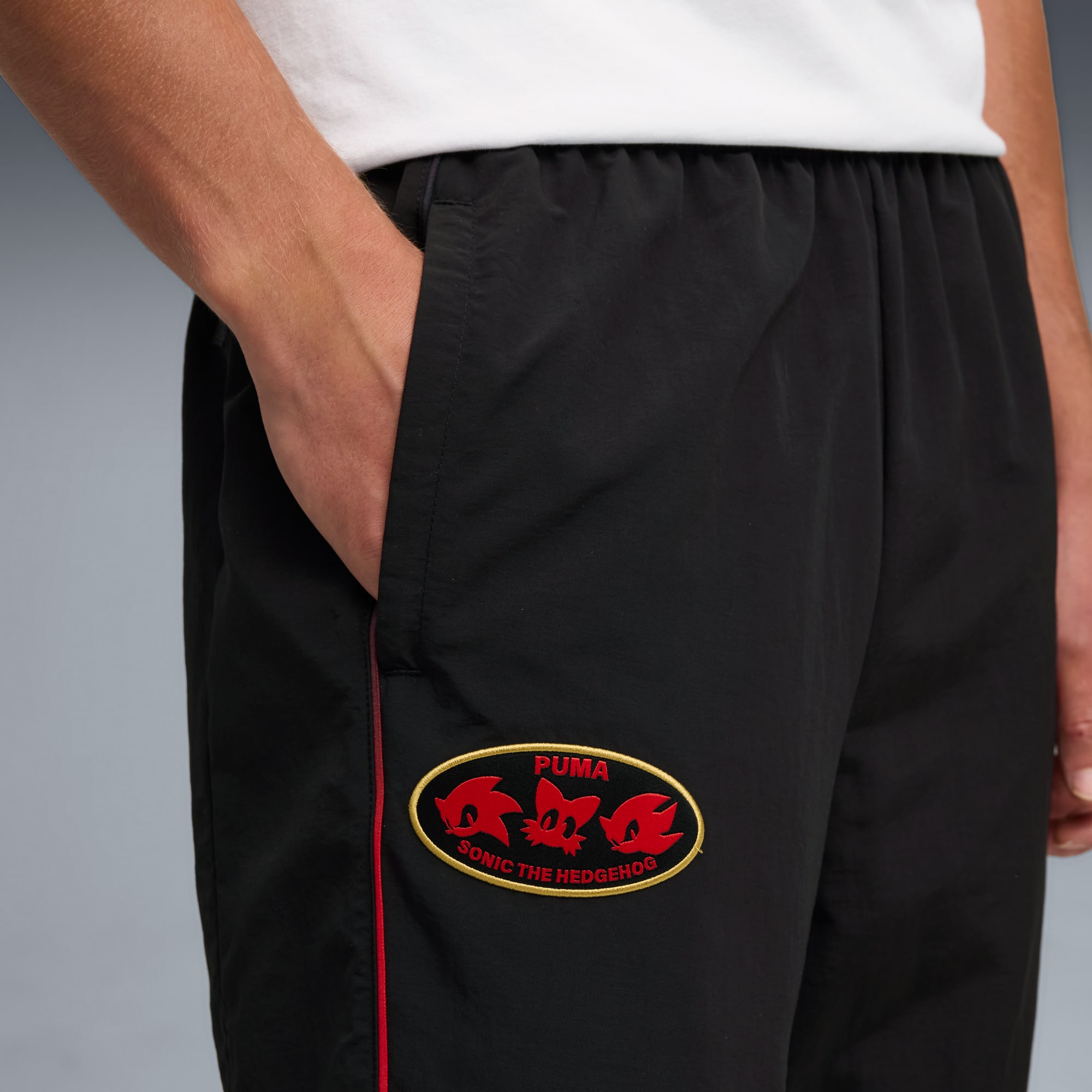 Primo piano di pantaloncini neri con patch di Sonic the Hedgehog su sfondo grigio.