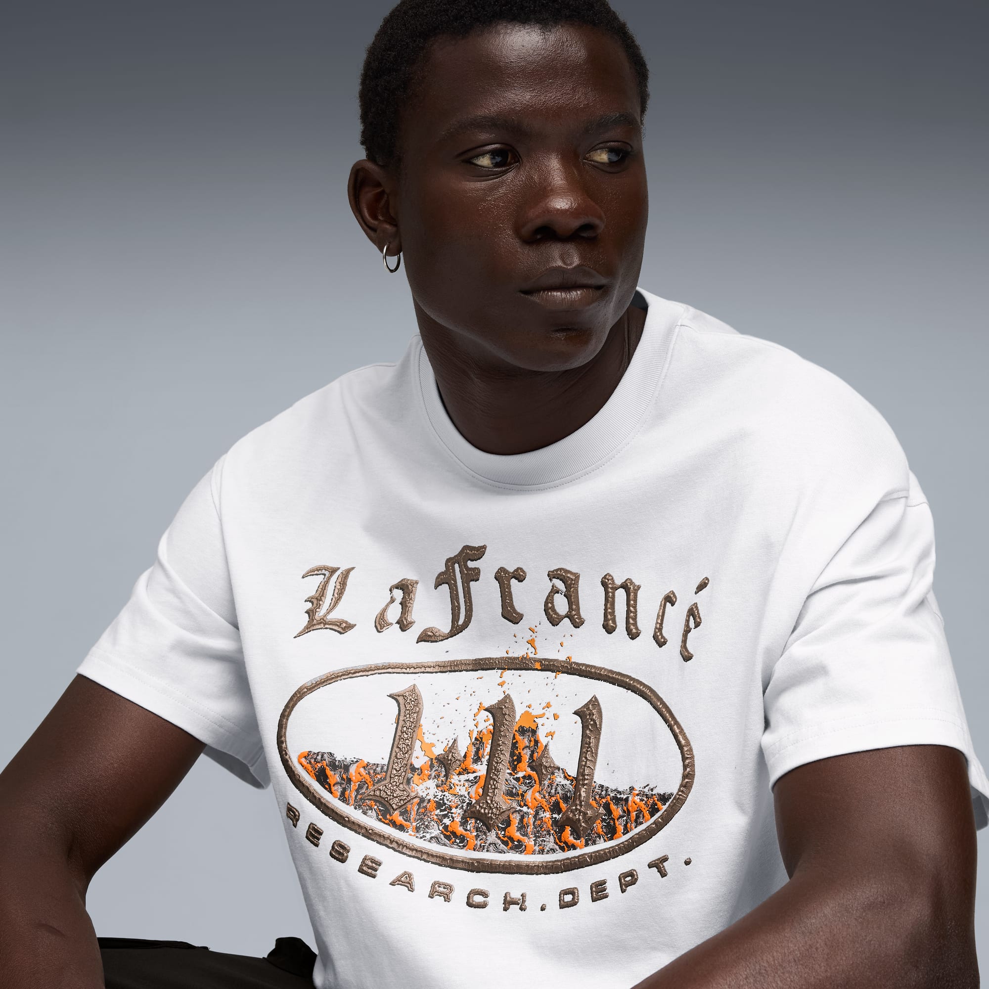 Un mannequin pose sur fond gris, portant un t-shirt blanc avec un imprimé graphique.