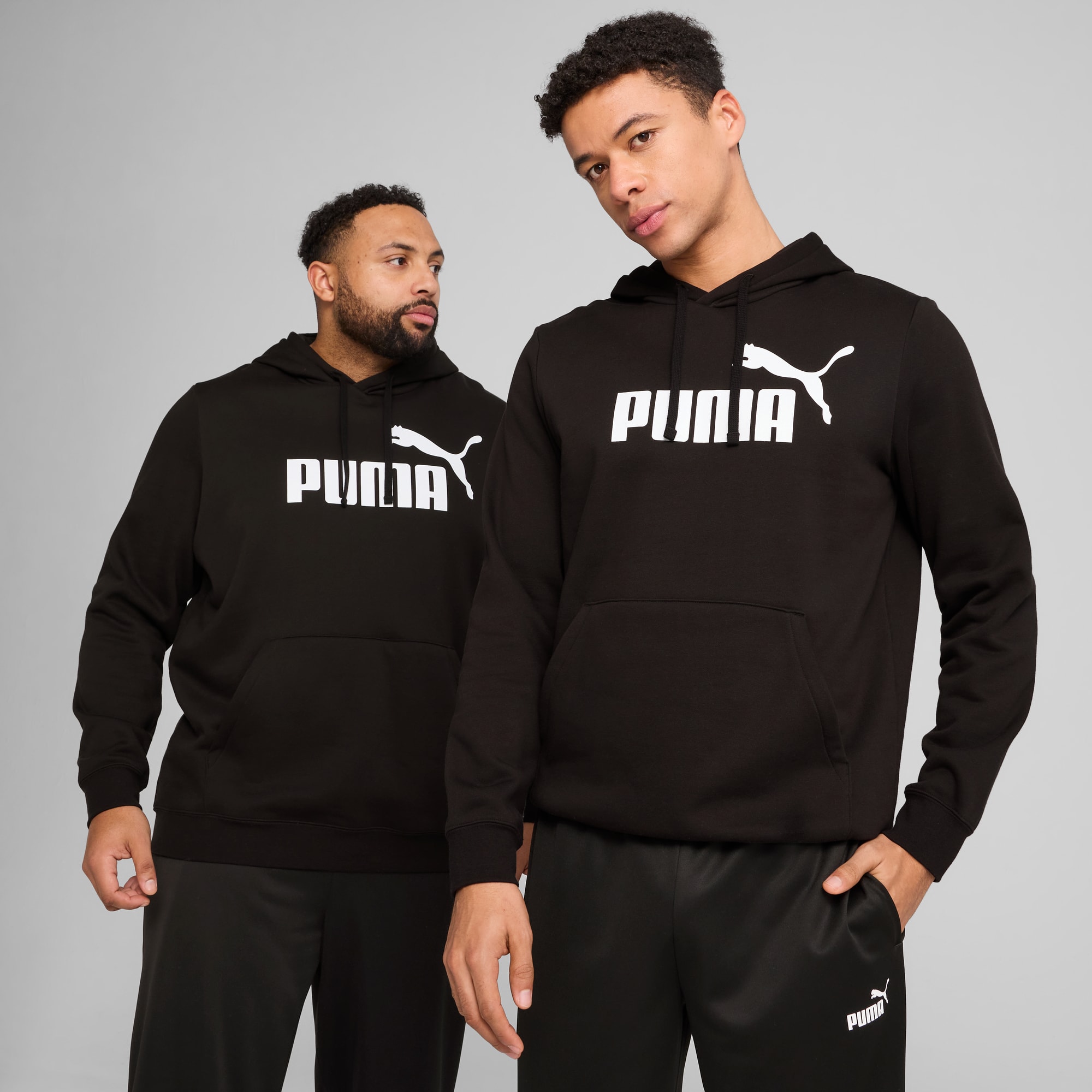 Deux modèles portent des sweats à capuche et des bas Puma noirs sur fond gris.