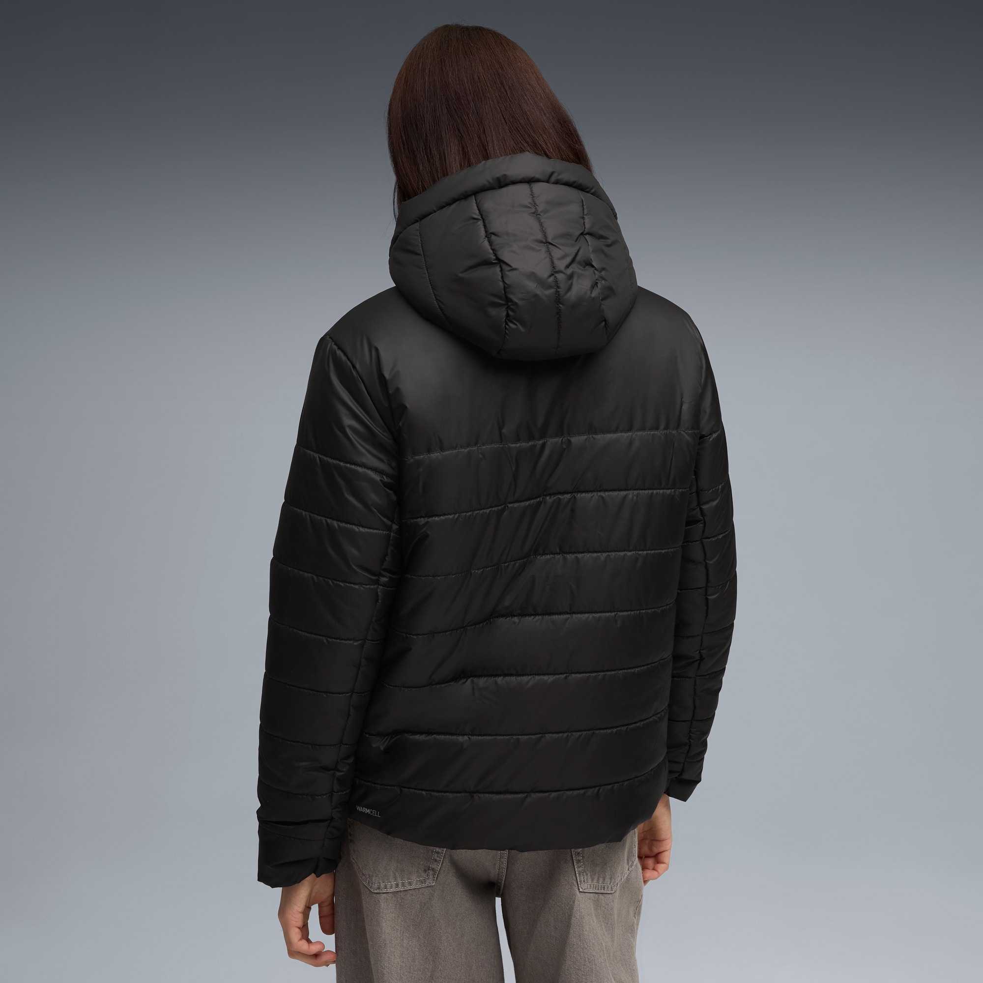 Een model met bruin haar, van achteren gezien, draagt een zwarte jas met capuchon.