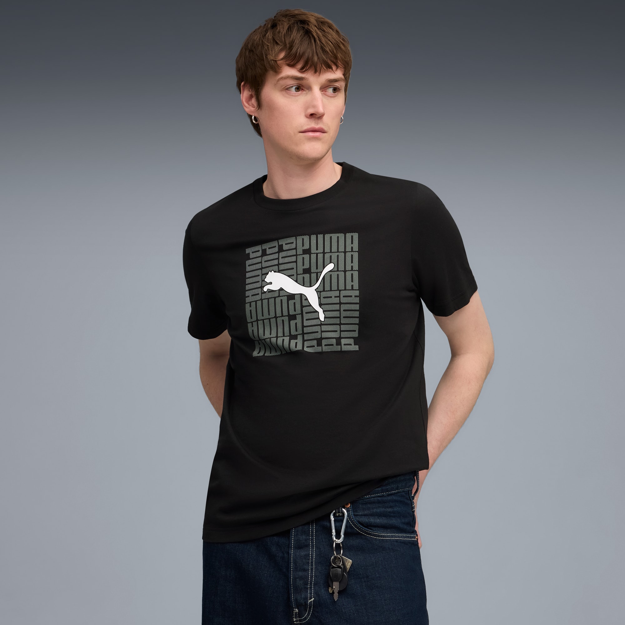 Een model poseert tegen grijs, gekleed in een zwart T-shirt met wit en grijs logo.