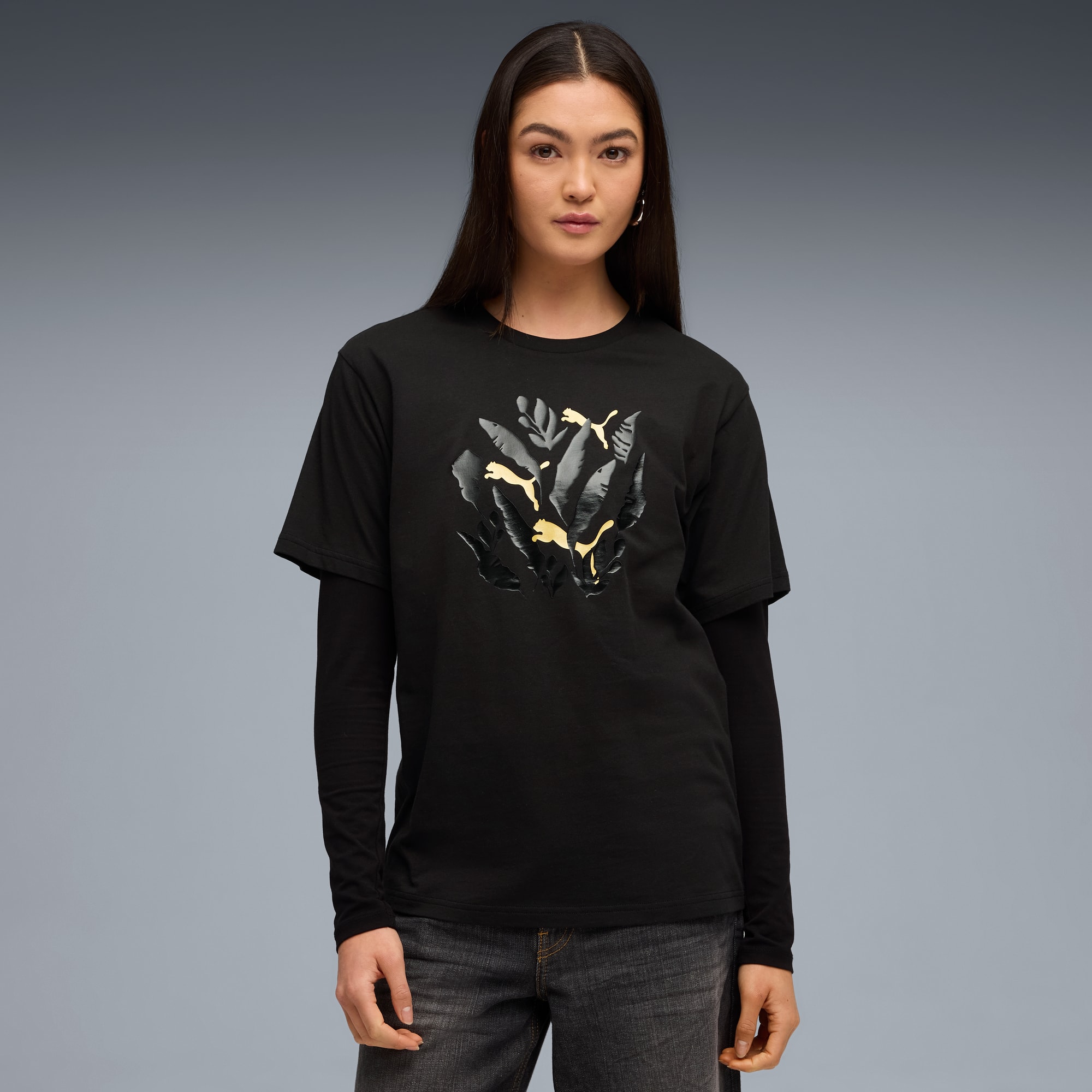 Ein Model posiert vor grauem Hintergrund und trägt ein schwarzes T-Shirt mit Grafikdesign.