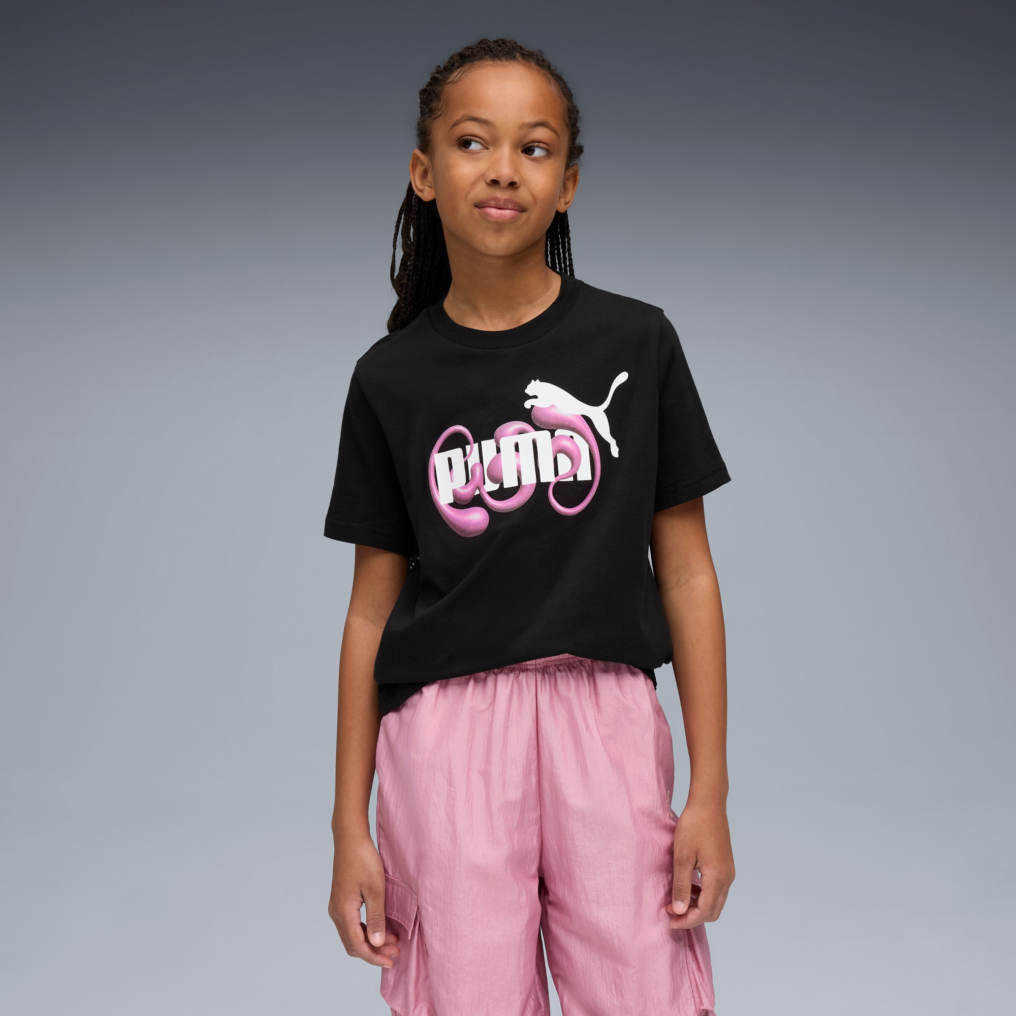 Su sfondo grigio, una modella indossa una t-shirt nera con logo Puma e pantaloni rosa.