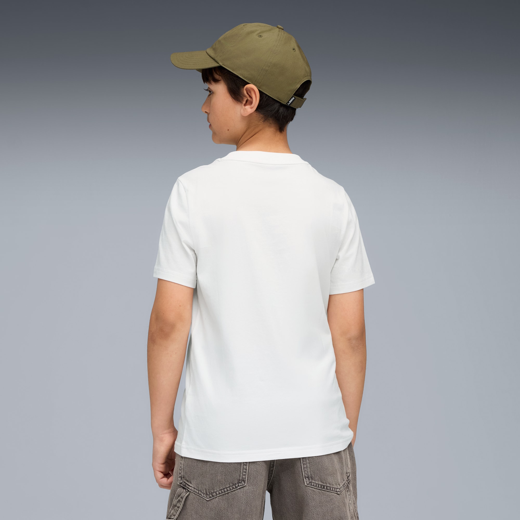 Een model staat met de rug naar de camera, op een grijze achtergrond, met een pet, wit t-shirt en grijze short.