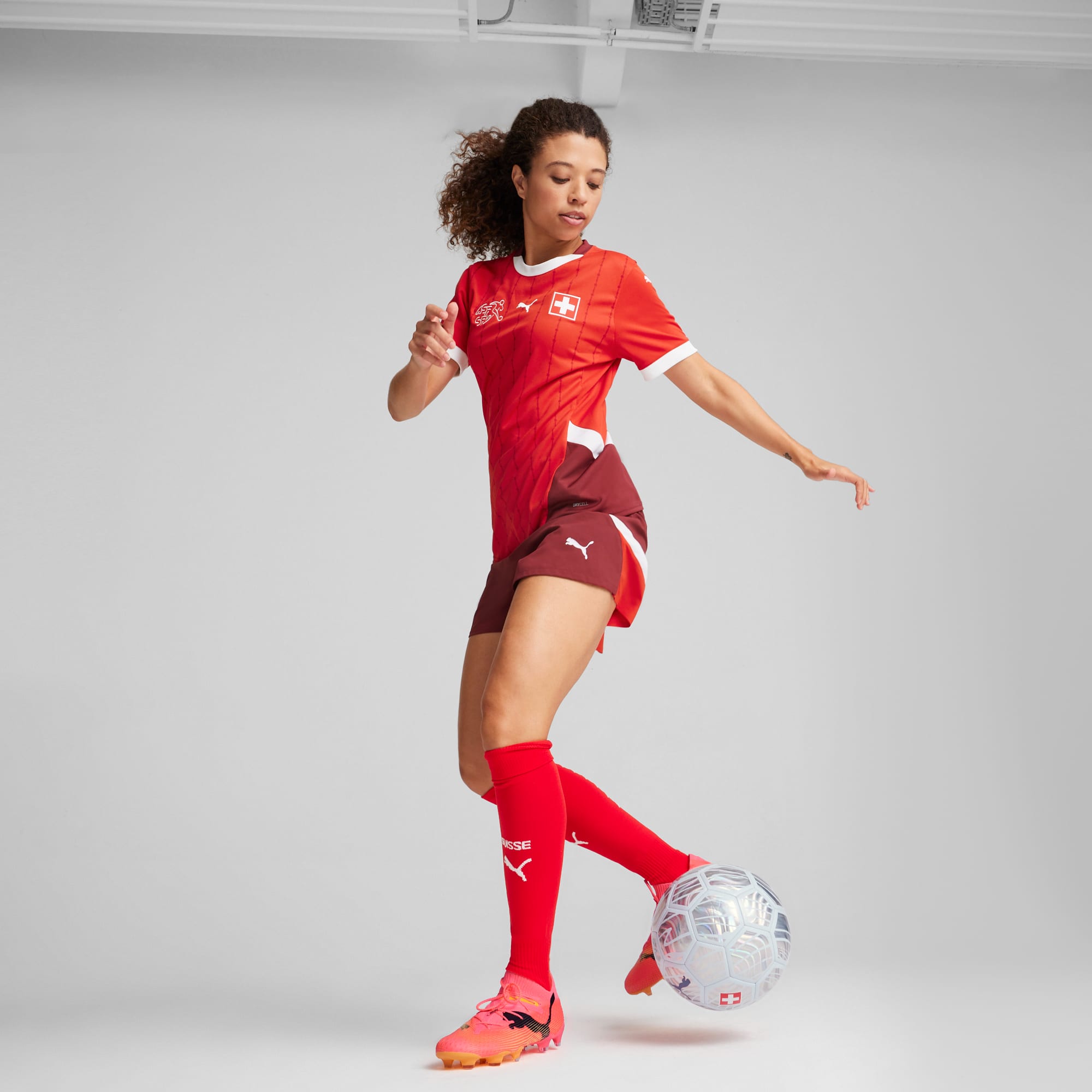 Sur fond gris, un mannequin joue au football vêtu d'un maillot rouge de la Suisse.