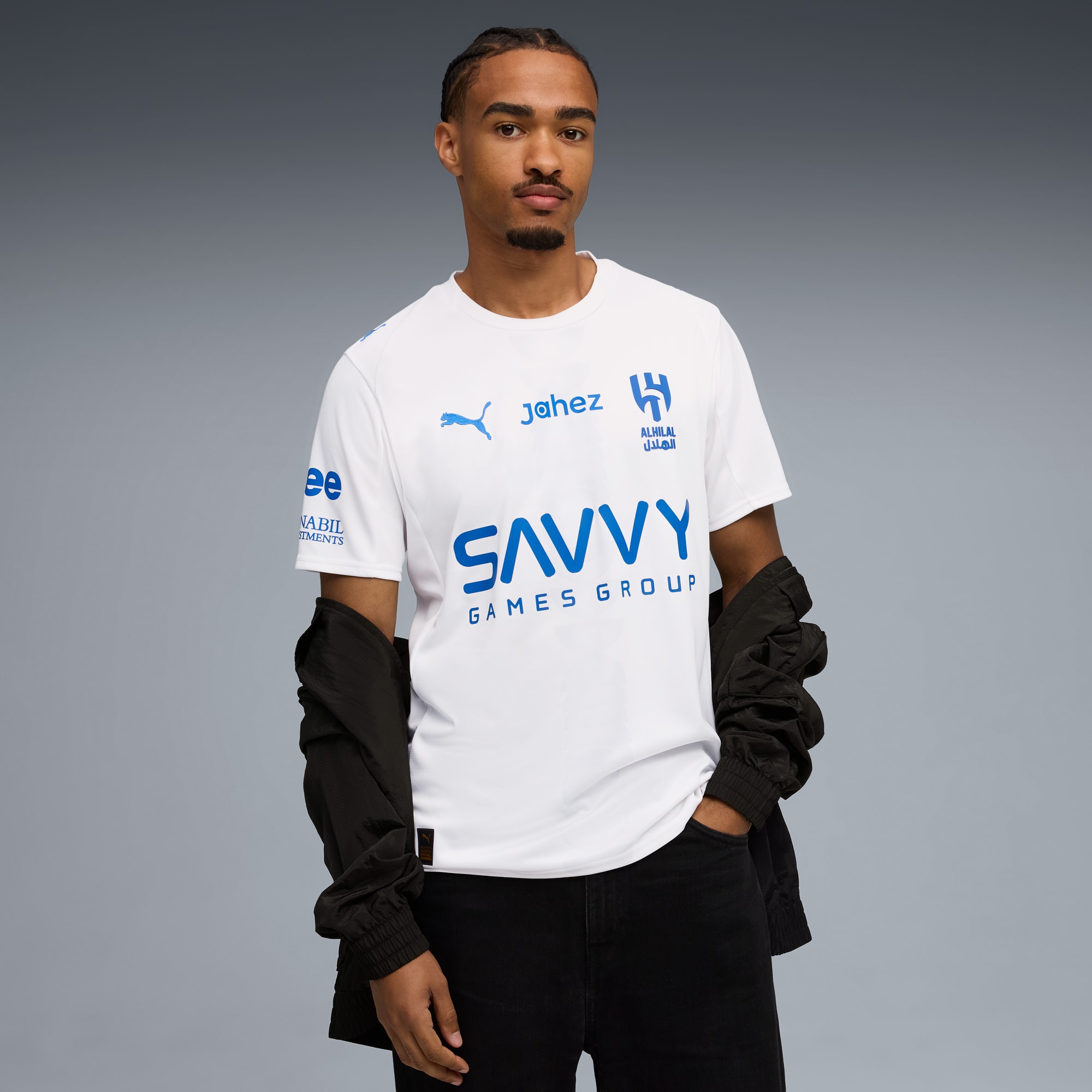 Un mannequin pose sur fond gris, portant un t-shirt blanc, un jean noir et une veste noire.