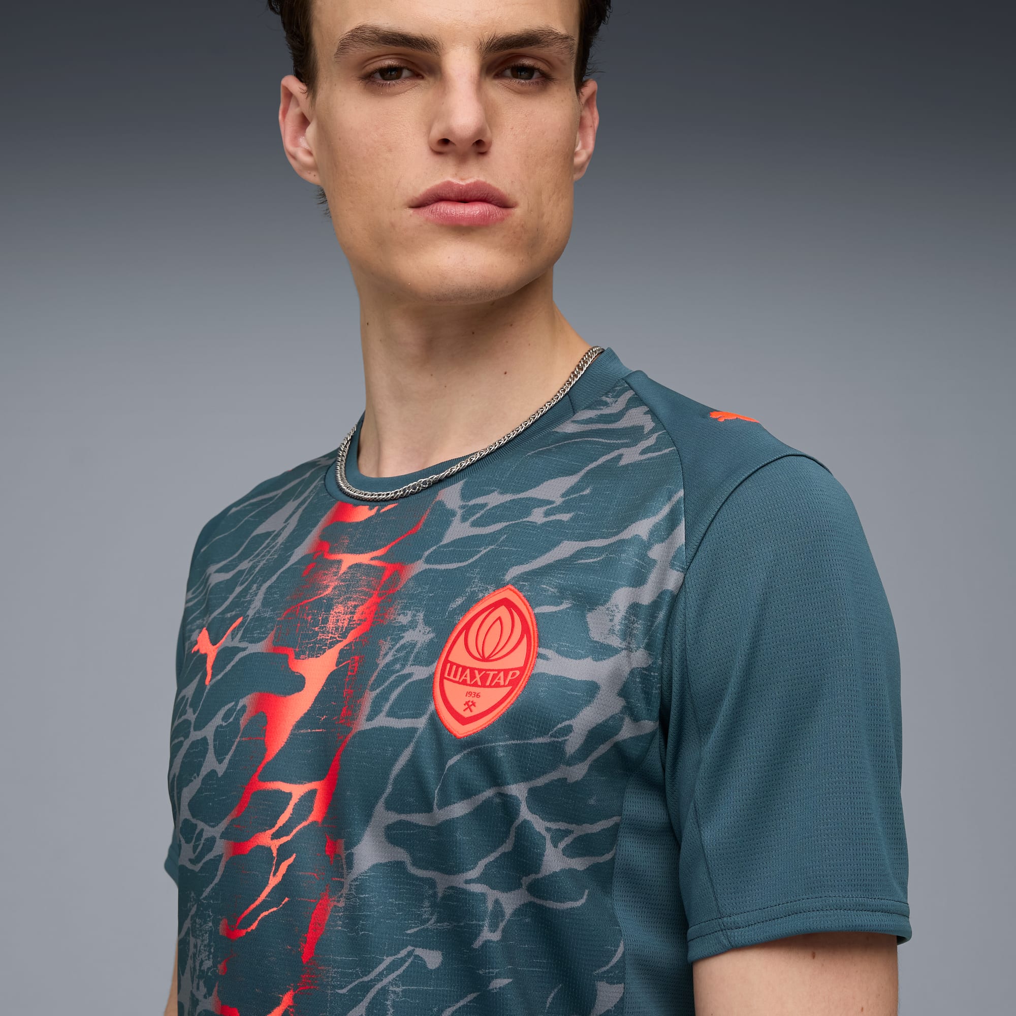 Tegen grijs draagt een model een shirt met patroon en het Shakhtar-logo.