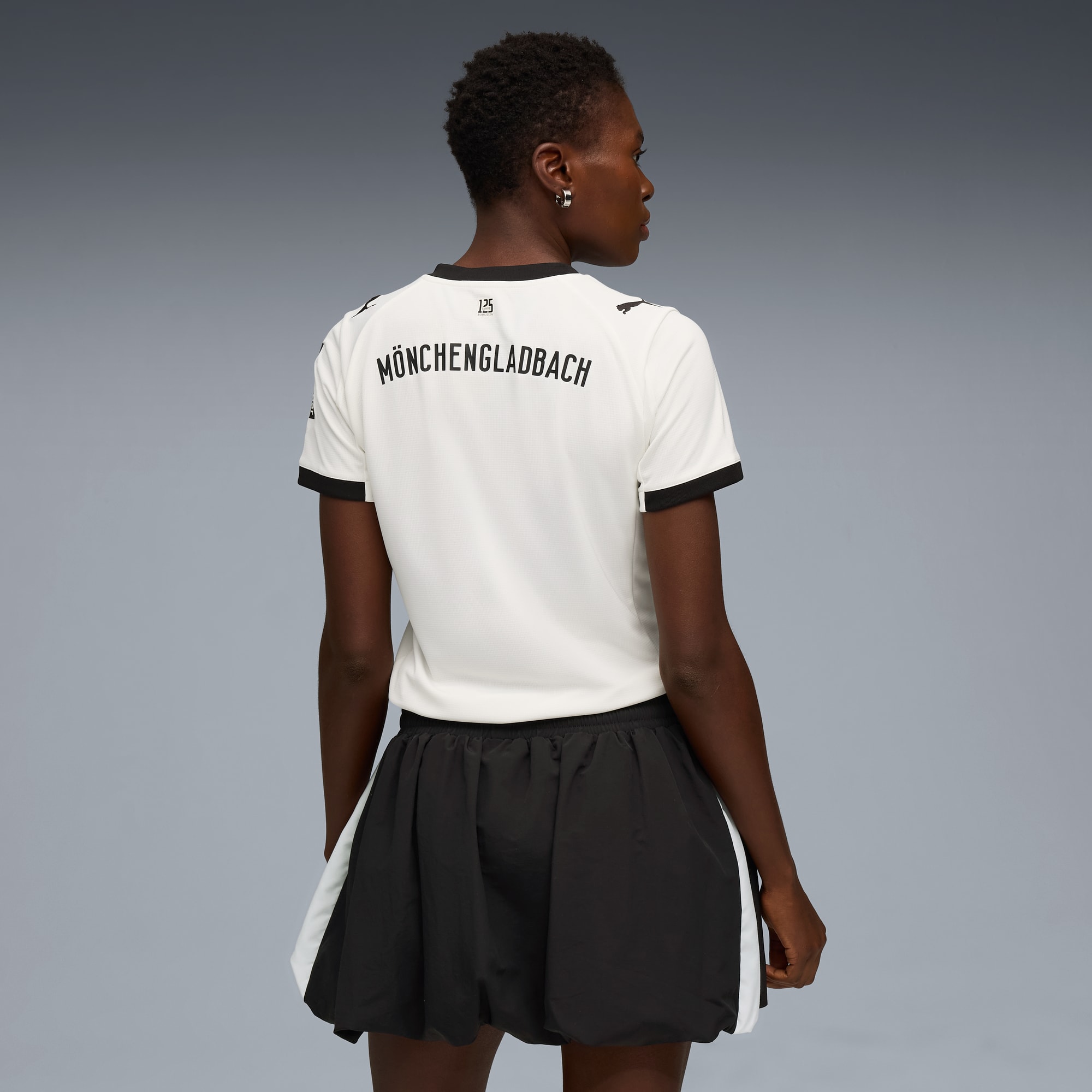 Un mannequin de dos sur fond gris, portant un t-shirt blanc et un short noir.