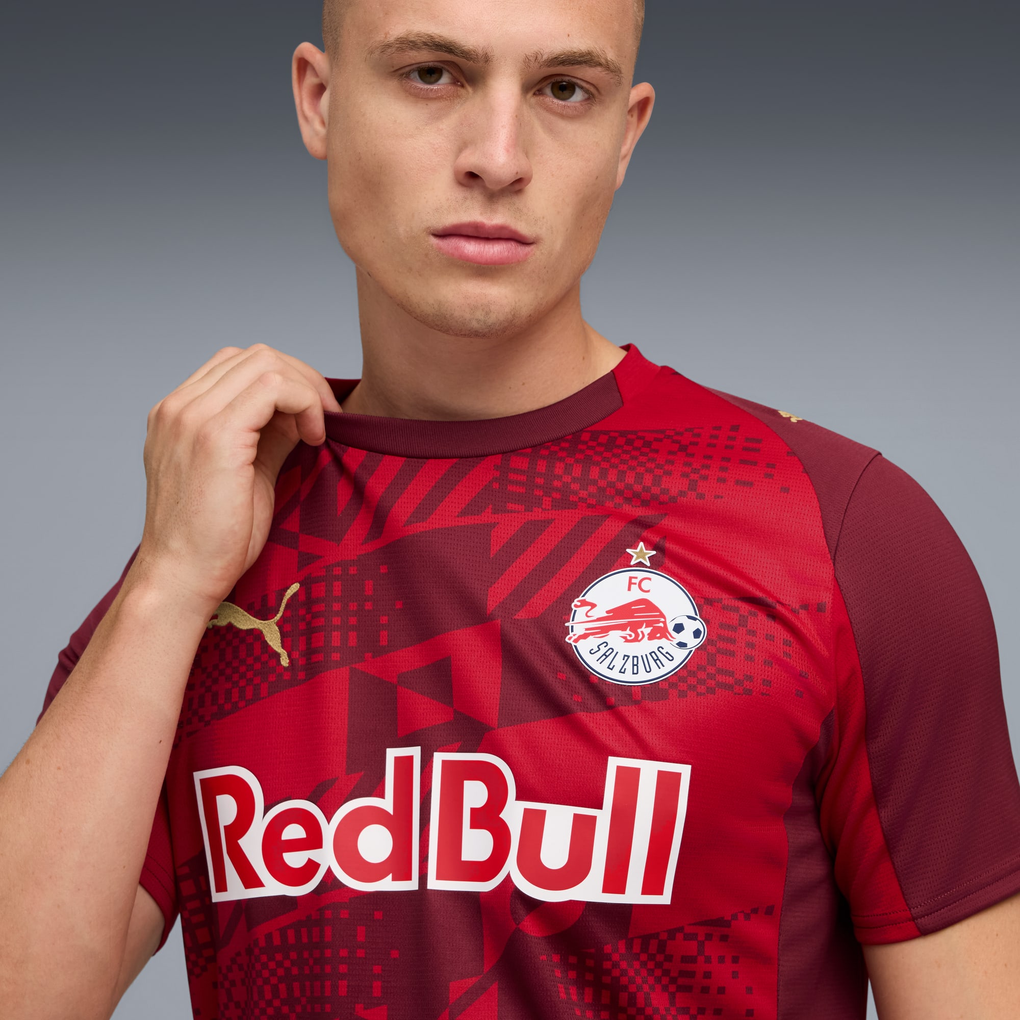 Een model voor een grijze achtergrond draagt een rood FC Salzburg t-shirt.