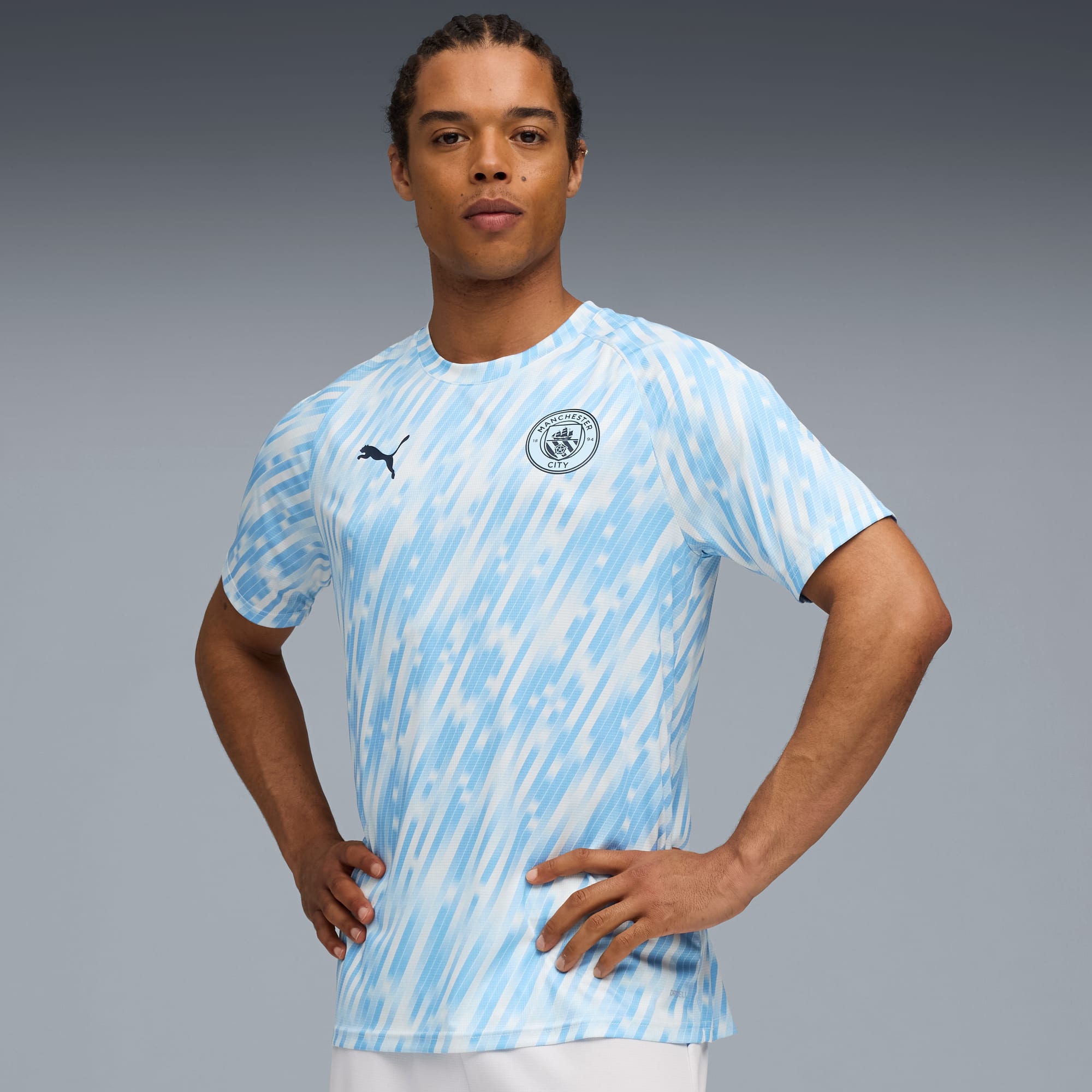 Un modello posa su sfondo grigio, indossando una t-shirt a motivi bianco e azzurro.