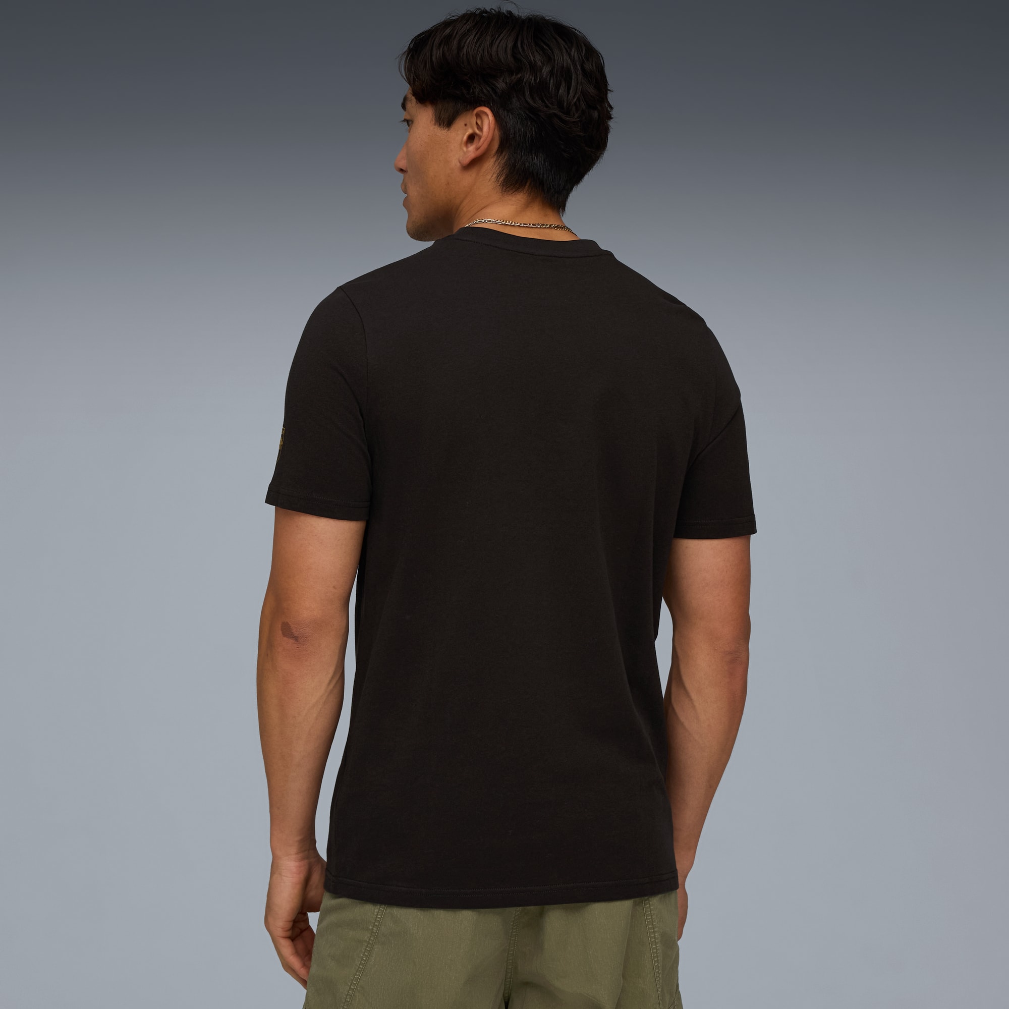 Un modèle de dos sur fond gris, portant un t-shirt noir et un short vert.